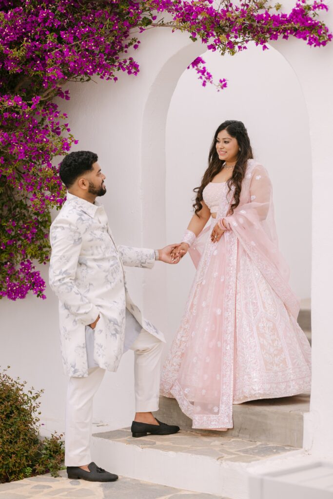 South Asian bride in a pink lehenga and groom beneath a bougainvillea-covered arch in Turkey