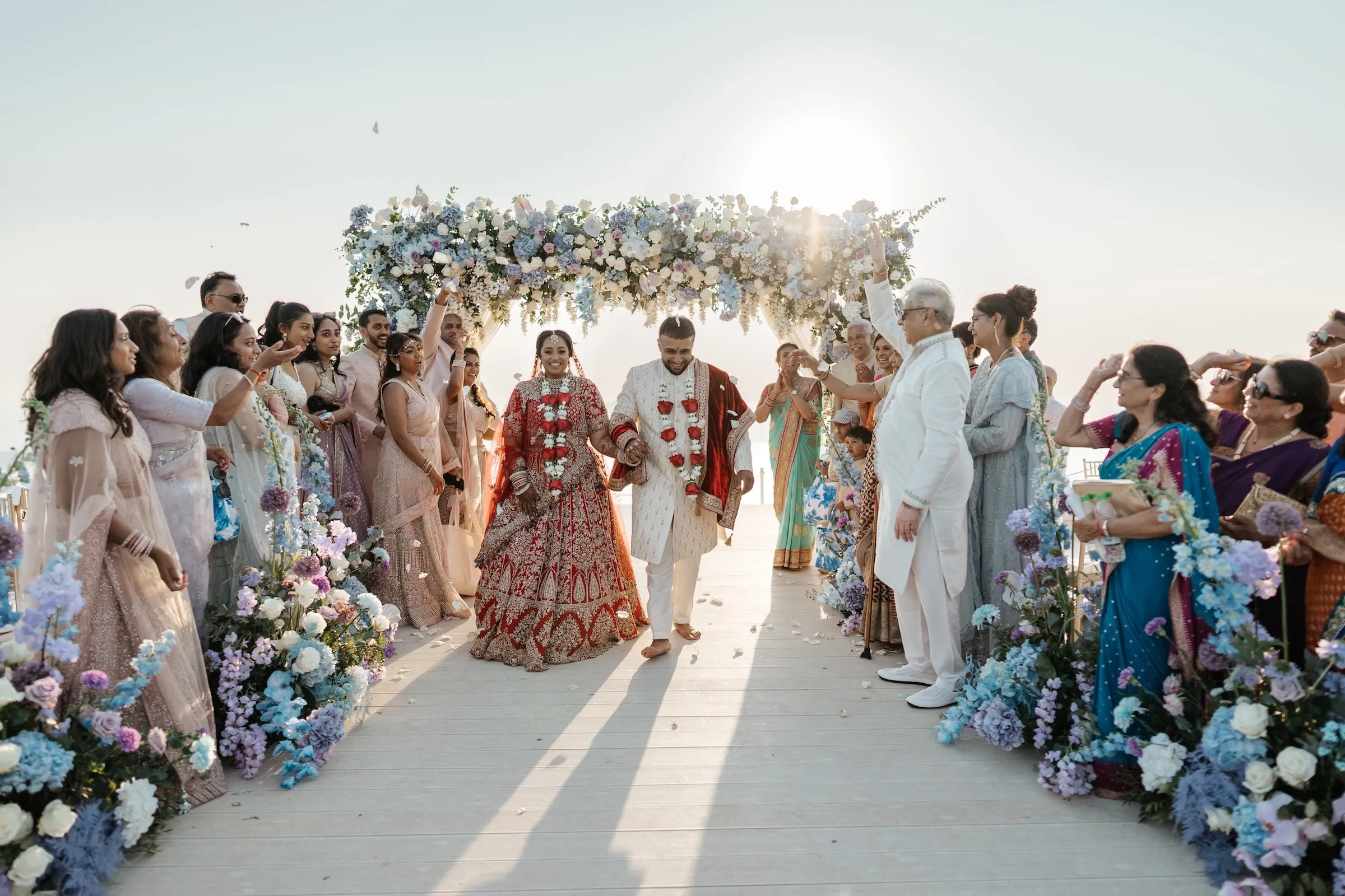 Bride and groom leaving a floral mandap as guests throw petals at a South Asian wedding abroad in Turkey
