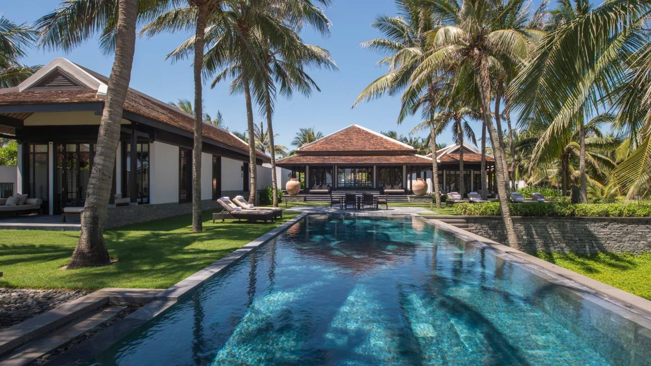 Beautiful swimming pool with villas and lounge chairs