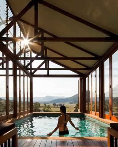 Woman in swimming pool with stunning view of fields and distant mountains