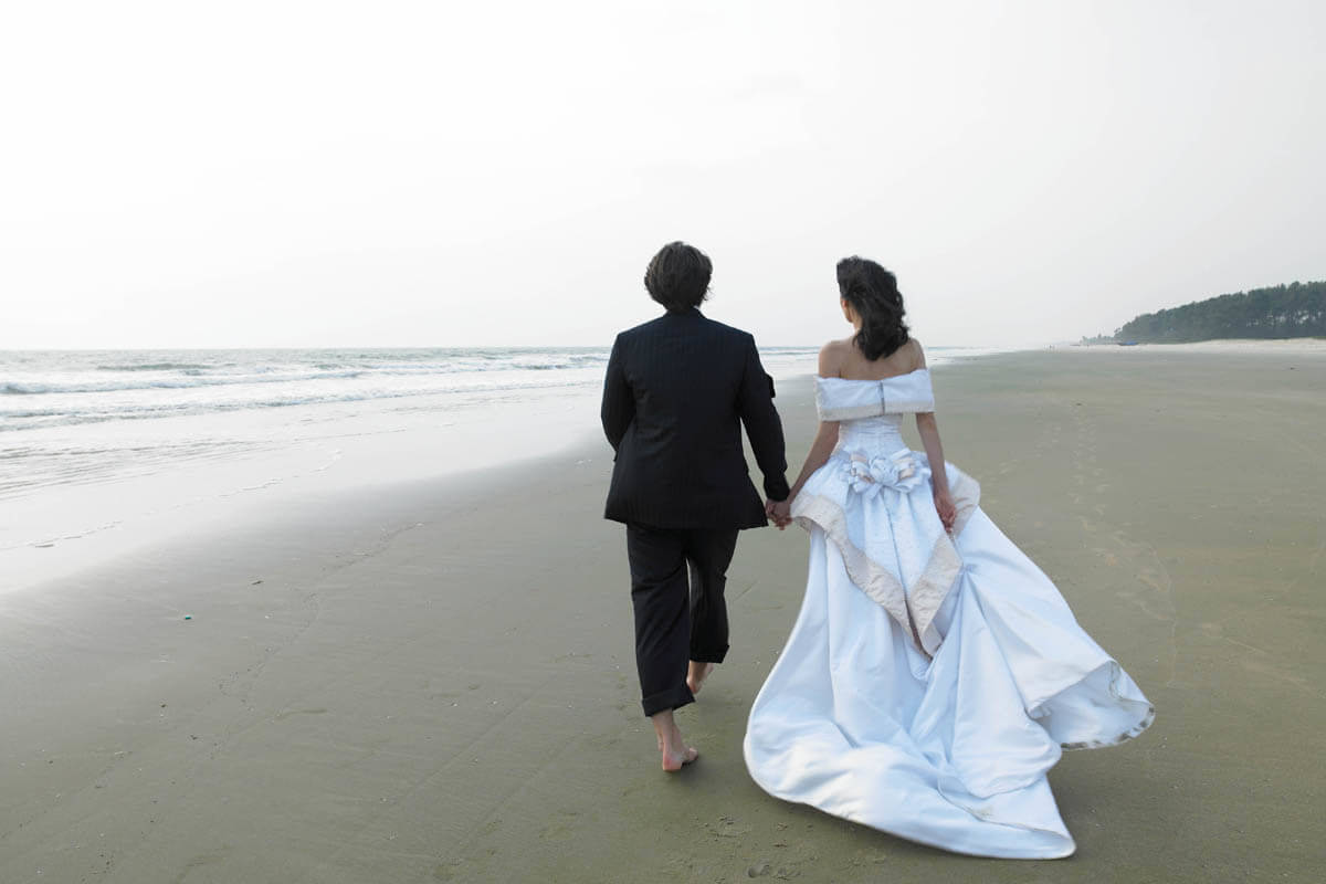 Wedding couple walking along the Zuri white sands in Salcete Goa, India